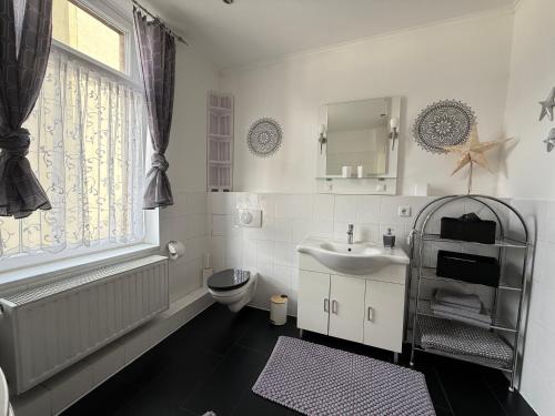 a bathroom with a sink and a toilet and a window at Ferienwohnung Roman Stadtkern von Quedlinburg 80qm in Quedlinburg