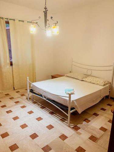 a bedroom with a bed in a room with a chandelier at Villino Emma in Santadi