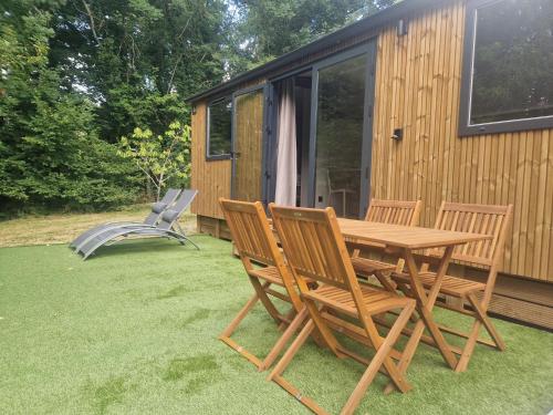 a picnic table and two chairs on a lawn next to a cabin at Cabane des Catalpas in Vollore-Ville