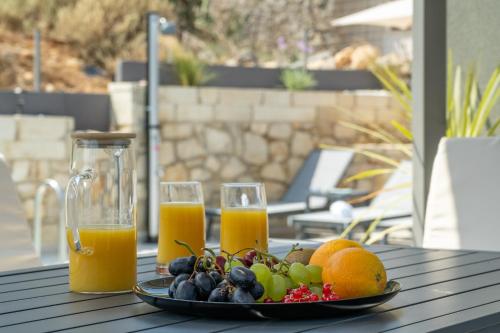 a plate of fruit and two glasses of orange juice at Echoes of Prinos in Metókhion Yianítsari
