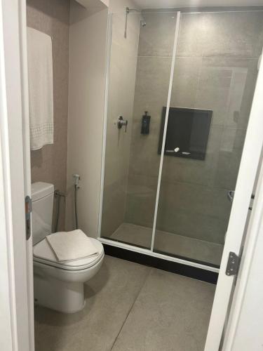 a bathroom with a toilet and a glass shower at Hotel Mega Polo in Sao Paulo