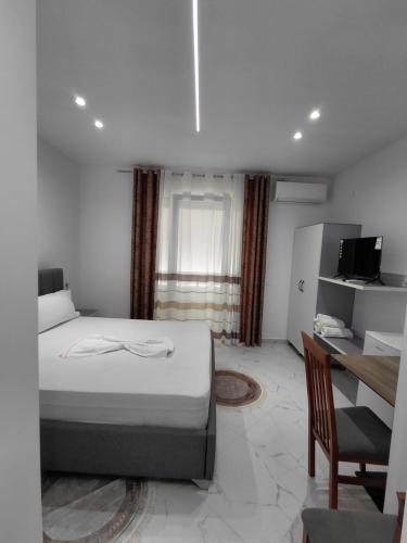 a bedroom with a bed and a desk and a television at Vila Kasemi in Fier