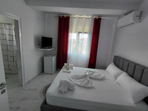a bedroom with a white bed and red curtains at Vila Kasemi in Fier