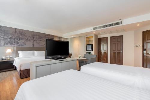 a hotel room with two beds and a flat screen tv at Grand Diamond Suites Hotel in Bangkok