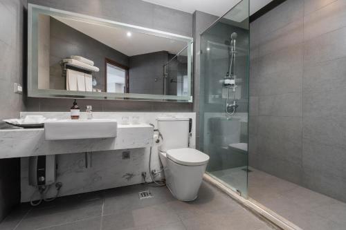 a bathroom with a toilet and a sink and a shower at Grand Diamond Suites Hotel in Bangkok