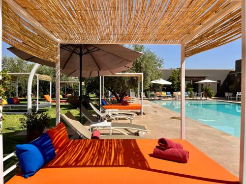 a swimming pool with an orange couch and an umbrella at Villa Jardins D'Isa in Marrakech