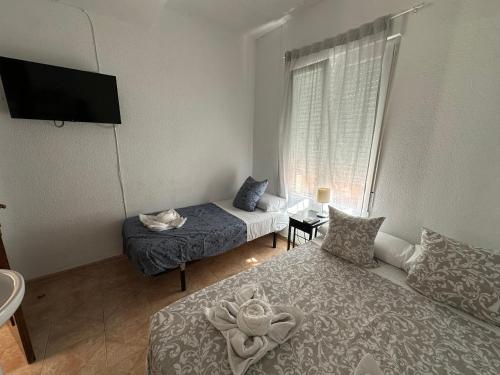 a small room with two beds and a window at Hostal Arrate in Madrid