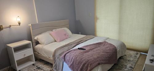 ein Schlafzimmer mit einem Bett mit einer rosa Decke darauf in der Unterkunft Lakeview Private Room in St Paul in Little Canada