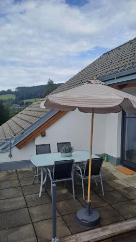 a table and chairs with an umbrella on a patio at Ski, bike, hike & chill! in Sankt Kathrein am Hauenstein