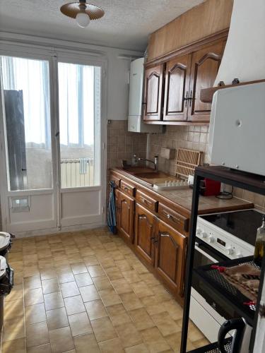 une cuisine avec des placards en bois et une grande fenêtre dans l'établissement Appartement proche stade Vélodrome, à Marseille
