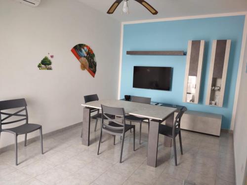 a dining room with a table and chairs and a tv at Appartamento Mozart 3 a Pescoluse in Marina di Pescoluse