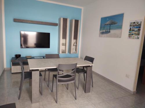 a dining room with a table and chairs and a television at Appartamento Mozart 3 a Pescoluse in Marina di Pescoluse