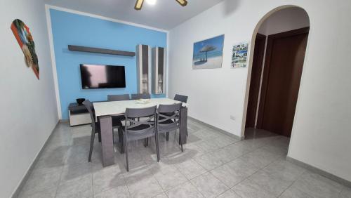 a dining room with a table and chairs and a tv at Appartamento Mozart 3 a Pescoluse in Marina di Pescoluse