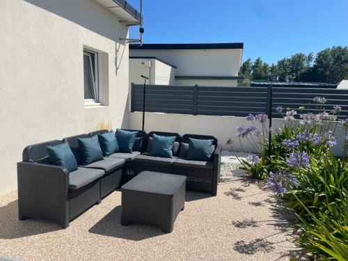 a patio with a couch with blue pillows on it at La maison Ti Billou in Santec