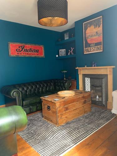a living room with a green leather couch and a fireplace at Stunning Beach house in Gorleston-on-Sea