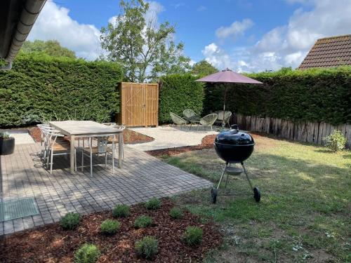 un grill in cortile con tavolo e ombrellone di Chocolat & Vanille a Koksijde