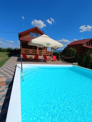 a swimming pool with an umbrella and a house at Vikendica sa bazenom Čarolija Kruševac in Kruševac