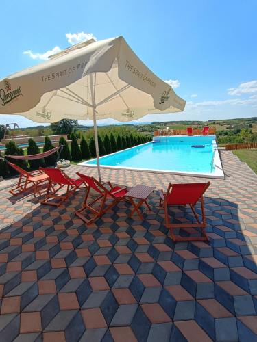 a patio with chairs and an umbrella and a swimming pool at Vikendica sa bazenom Čarolija Kruševac in Kruševac