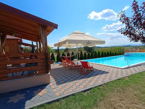 a house with a swimming pool and an umbrella at Vikendica sa bazenom Čarolija Kruševac in Kruševac