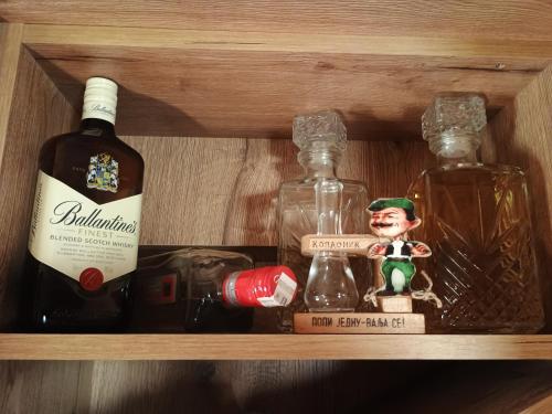 a wooden shelf with bottles of alcohol and a doll at Vikendica sa bazenom Čarolija Kruševac in Kruševac