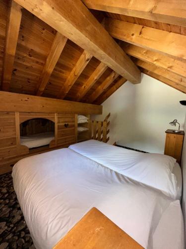a bed in a room with wooden ceilings at Hôtel-Chalet les Mélèzes in Valloire