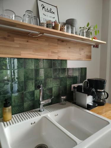 a kitchen sink with a green tile back splash at Vakantiewoning De Woestijn - De Schuur in Roosdaal