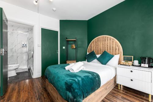 a bedroom with a bed with a green wall at City Gate Guest House in London