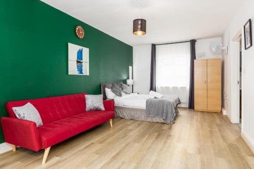 a living room with a red couch and a bed at City Gate Guest House in London