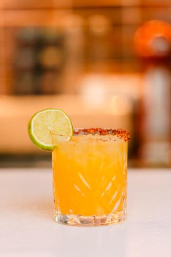 a glass of orange juice with a lime at Eleni Rooms in Parikia