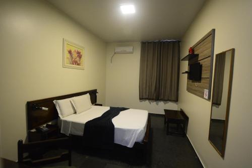 a hotel room with a bed and a window at Hotel Monte Pascoal in Itamaraju