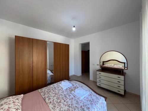 une chambre avec un lit, une commode et un miroir dans l'établissement Reys Central Orikum 2-Bedroom Apartment for Five, à Polisi i Vogël
