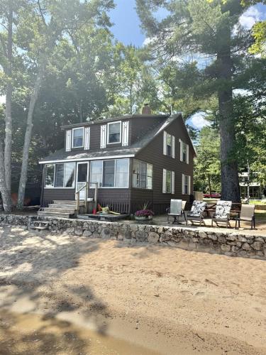 a large black house with chairs and trees at CAMP LINDY LIMIT 7 cottage in North Sebago