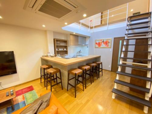 a kitchen with a large island with bar stools at 城崎 柳通り ゆるり-Yururi- in Toyooka