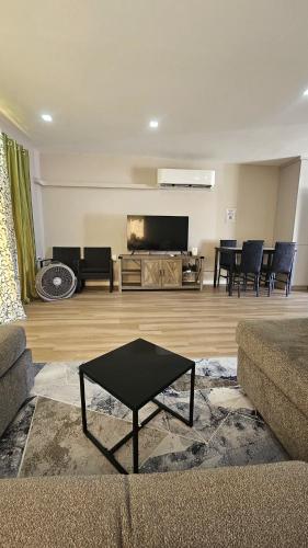 a living room with a couch and a tv and a table at Soleil Serenity - Relax & Unwind in Dabadie