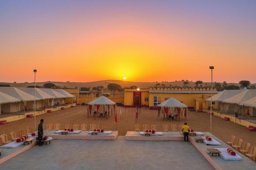 a group of tents in front of a sunset at Melody Moon Desert Camp & Resort in Jaisalmer