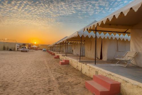 a building in the desert with a sunset in the background at Melody Moon Desert Camp & Resort in Jaisalmer
