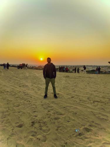 a man standing on the beach watching the sunset at Melody Moon Desert Camp & Resort in Jaisalmer