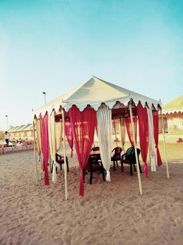 a tent on the beach with tables and chairs at Melody Moon Desert Camp & Resort in Jaisalmer