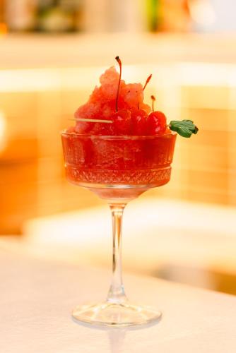 a drink in a wine glass with cherries in it at Eleni Rooms in Parikia