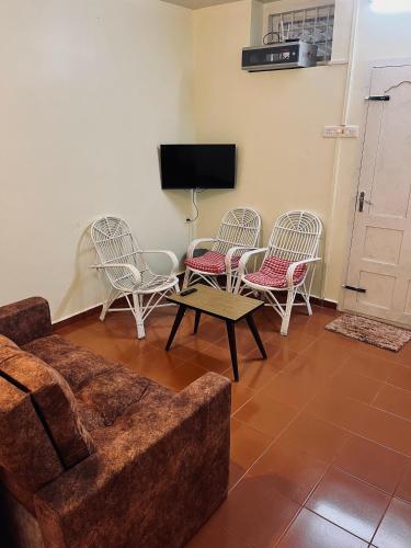 a living room with chairs and a couch and a tv at MARUTHY FARM HOUSE in Vandanmedu