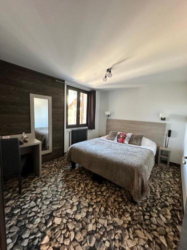 a bedroom with a bed and a desk and a window at Hôtel-Chalet les Mélèzes in Valloire
