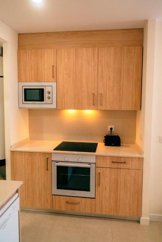 a kitchen with wooden cabinets and a microwave at Apartamentos Costa Norte in San Vicente de la Barquera