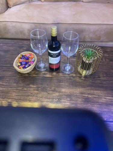 a bottle of wine and three wine glasses on a table at Morgan Hill Residence in Abuja