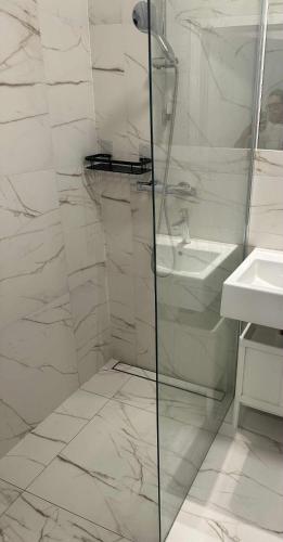 a white bathroom with a shower and a sink at Airport Apartment Okęcie in Warsaw