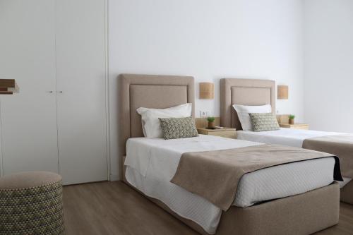 a bedroom with two beds and a stool at Curtido House Suits in Ílhavo