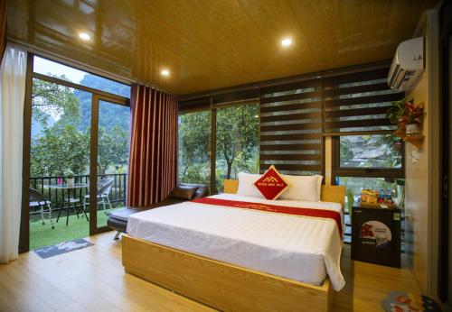 a bedroom with a large bed and a balcony at Hoang Minh Mountainside Villa in Ninh Binh