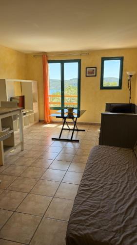 a room with a couch and a table and windows at Les Haut Du Lac in Sainte-Croix-de-Verdon
