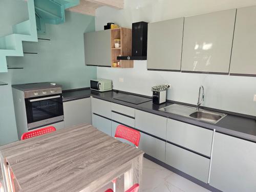 a kitchen with white cabinets and a table with red chairs at La casetta in collina albissola in Stella