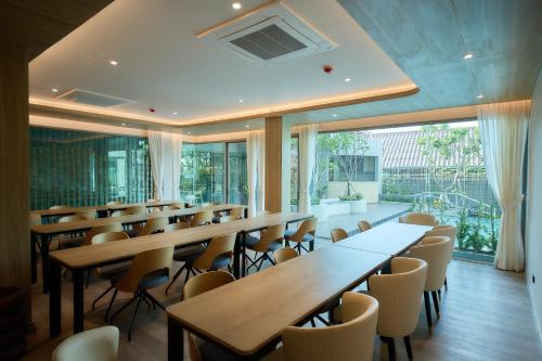 a row of tables and chairs in a room with windows at Unya Hotel Ubon - โรงเเรมอัญญาอุบล in Ban Na Khwai