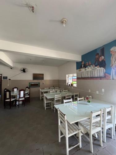 un comedor con mesas y sillas y una pintura en la pared en Hotel Maceió 3 irmãos, en Juazeiro do Norte